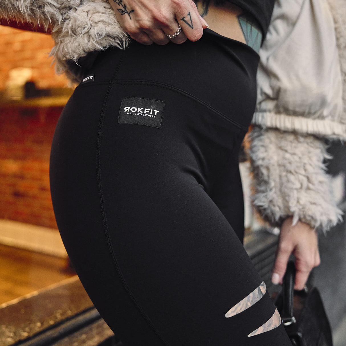 Female model outdoors wearing Cutline Leggings showing logo