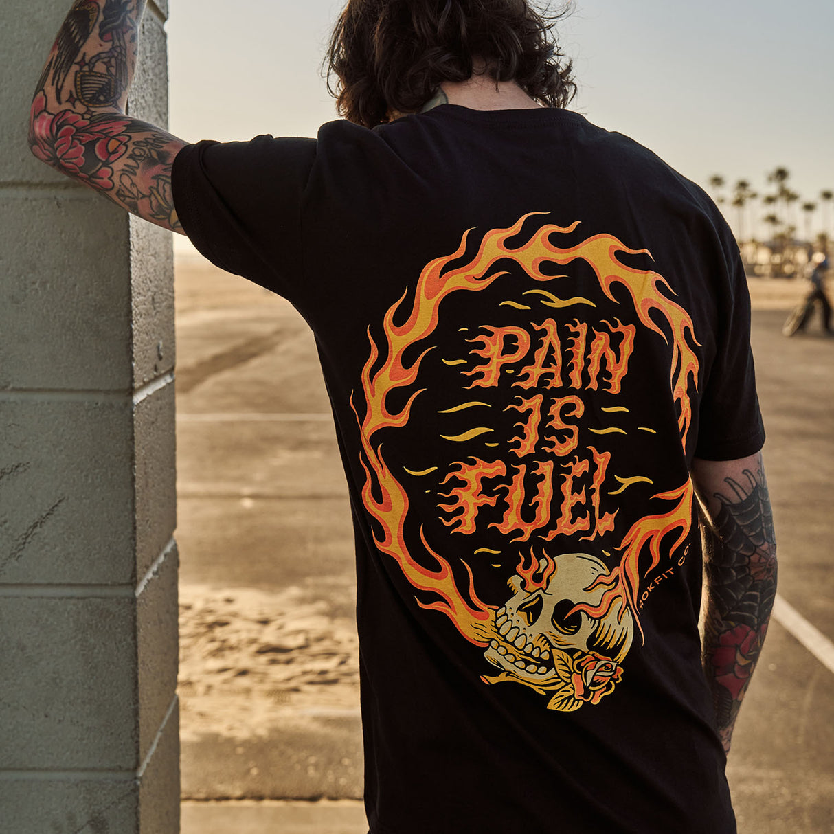 Male model outdoors wearing unisex Active Tee with 'Pain Is Fuel' graphic