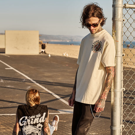 Male model outdoors wearing unisex Street Tee with 'Excuses or Reasons' graphic