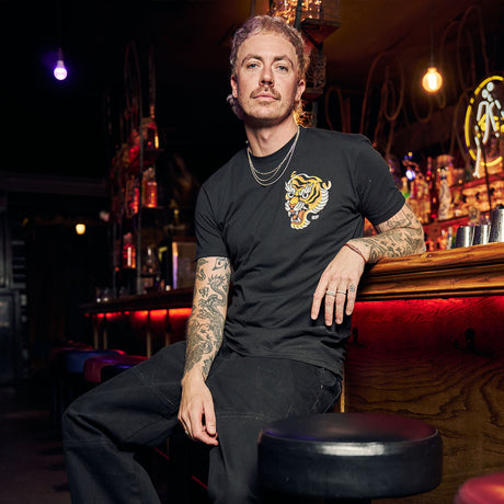 Male model in bar wearing black Active Tee with 'Make Excuses or Make Progress' graphic