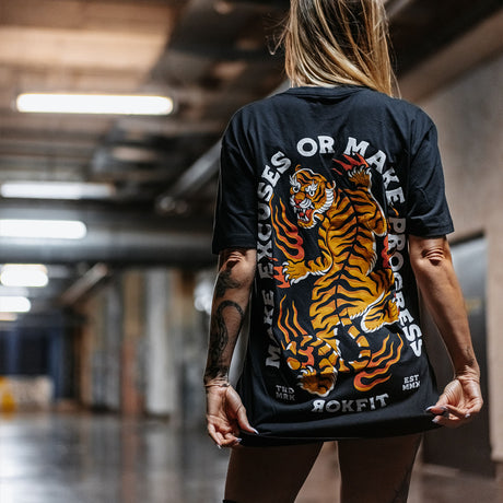 Female model outdoors wearing unisex Active Tee with 'Make Excuses or Make Progress' graphic